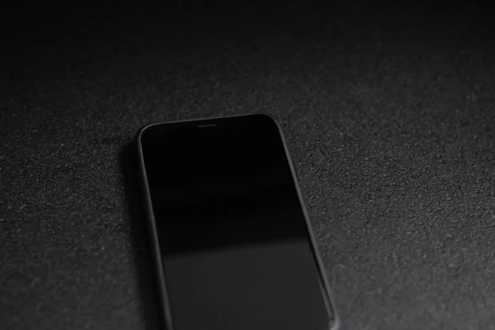 A smartphone resting face-up on a dark textured surface